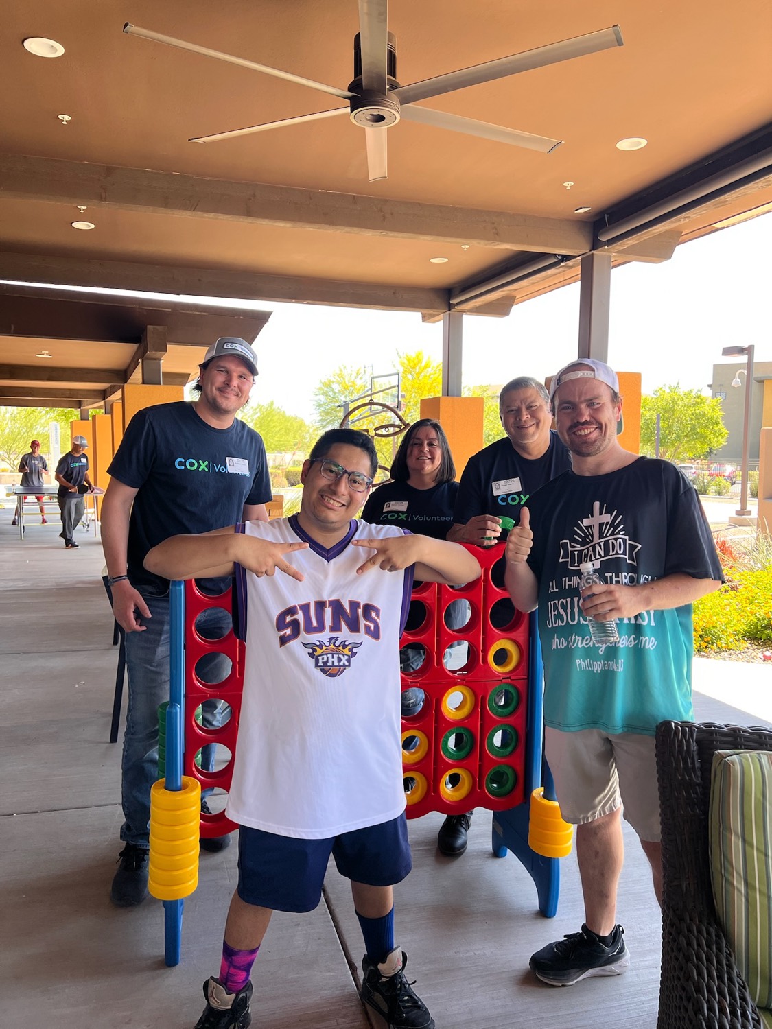 Treasure House residents and staff playing giant Connect Four together on the patio
