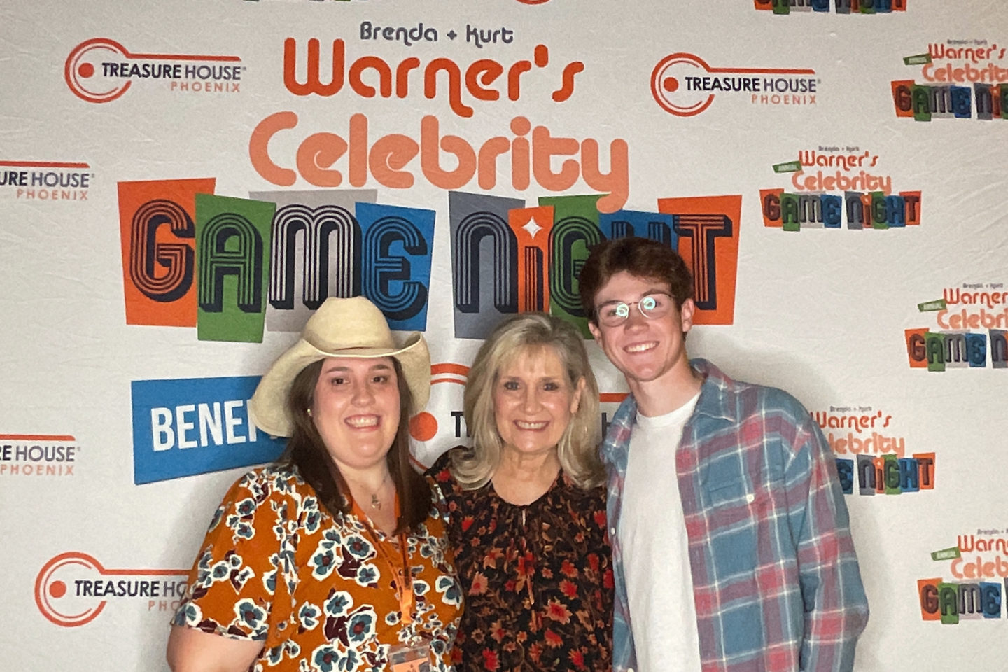 Three people pose in front of the celebrity game night logo