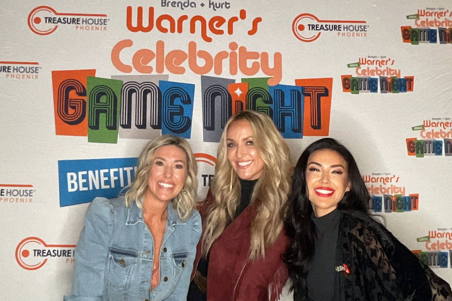 Three women pose in front of the celebrity game night logo