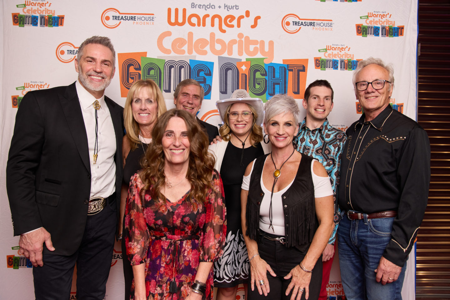 A group of people pose with Kurt and Brenda warner in front of the celebrity game night logo